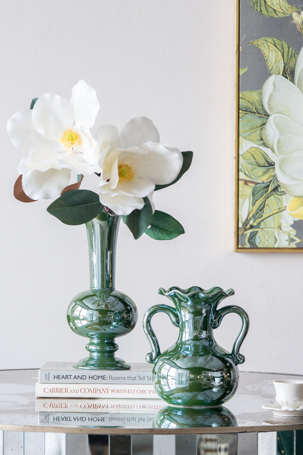 Emerald green ceramic vase with bulbous base and tall neck holding white magnolia blooms