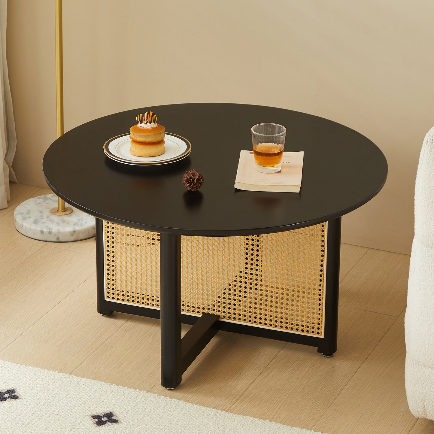 Round black coffee table with rattan inlay and modern black legs