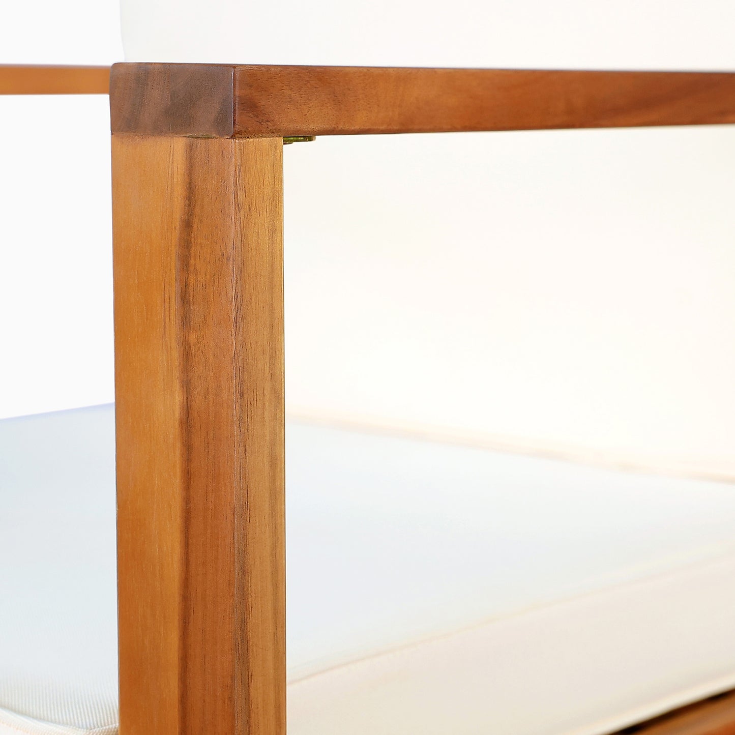 Closeup of a natural wood armchair frame with plush white cushions