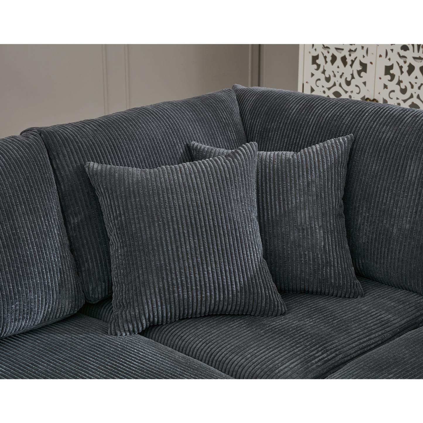 Closeup of a dark grey corduroy sofa with two matching throw pillows