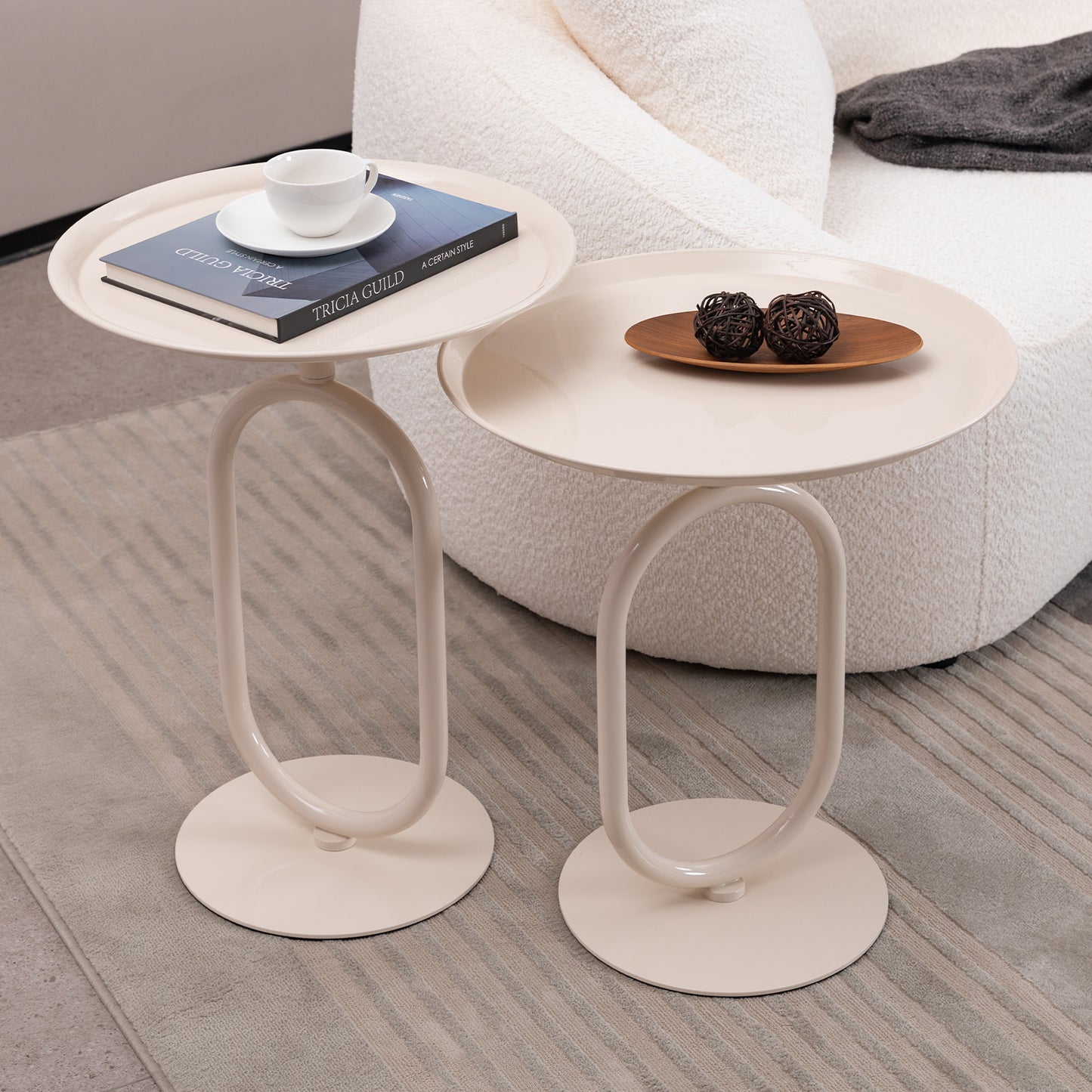 Pair of cream Cshaped side tables with round tops featuring a book and cup