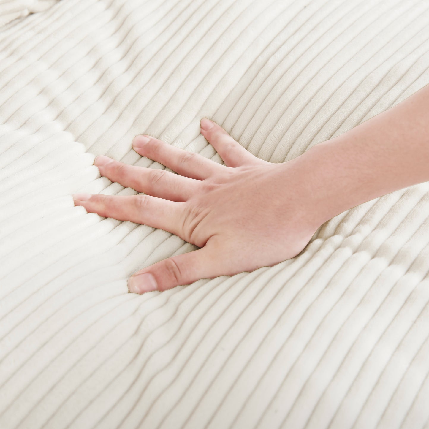 Hand pressing into plush cream corduroy fabric demonstrating softness