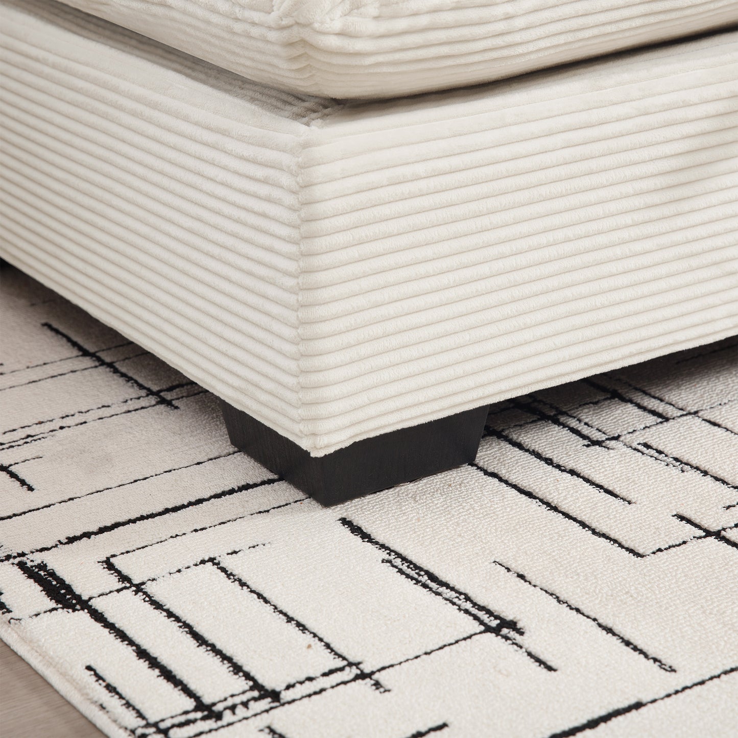 Cream corduroy sofa corner detail resting on a geometric black and white rug