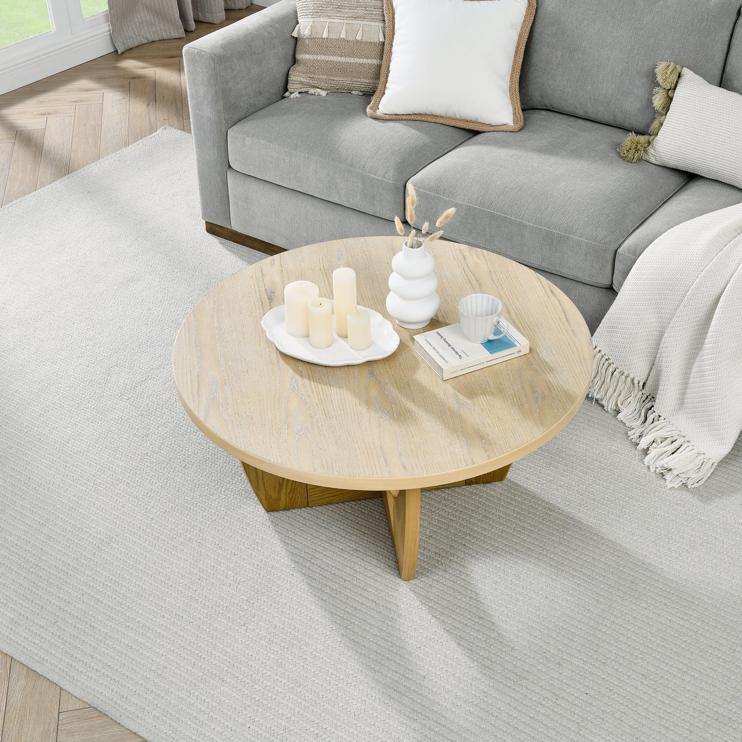 Light gray textured sofa with cream and beige decorative pillows and a white throw blanket