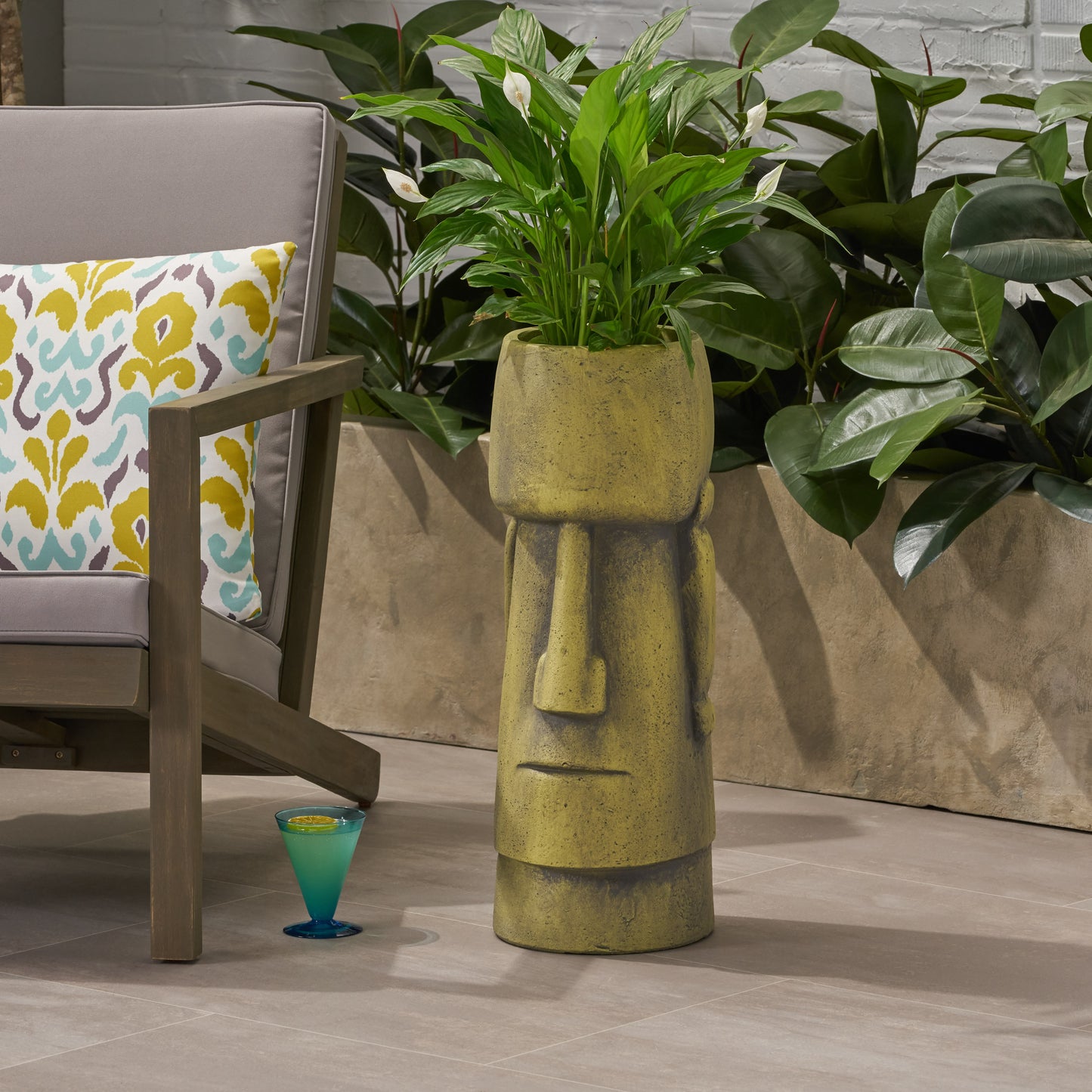 Textured yellow stone planter resembling a Moai statue holding a peace lily plant