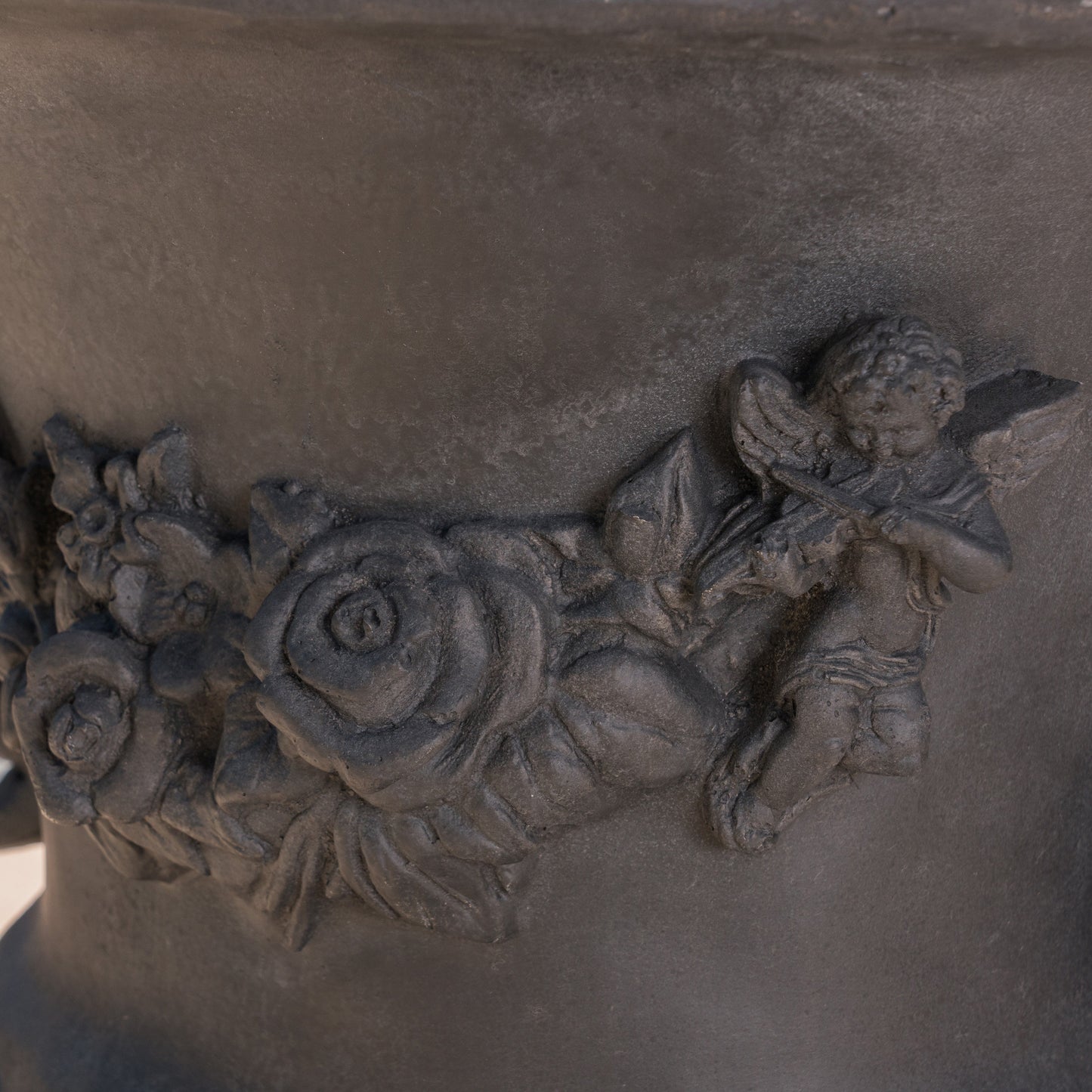 Dark grey stone planter with an ornate cherub and rose relief antique garden decor