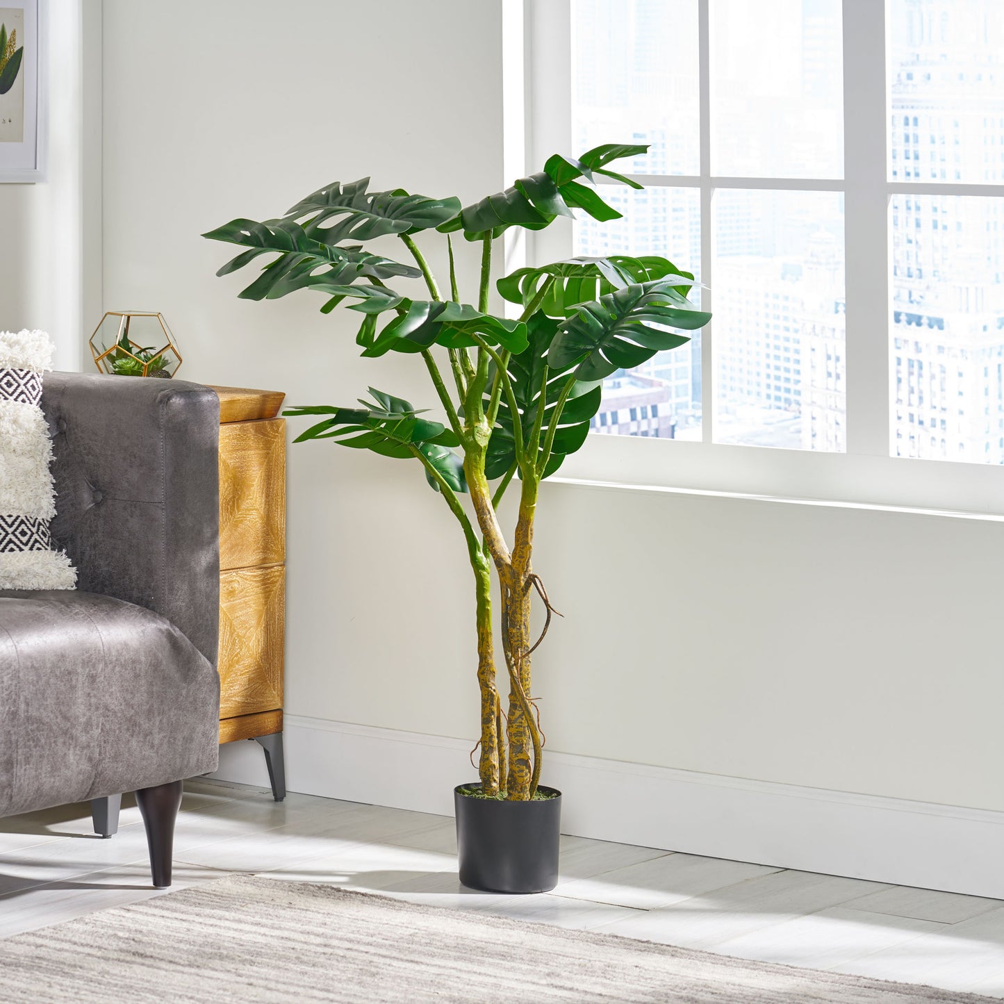 Large artificial Monstera plant in a black pot adding lush greenery to living spaces