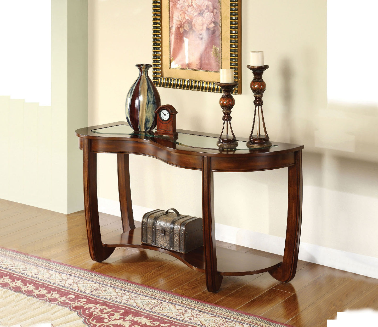 Curved dark wood console table with glass top and lower shelf holding decorative items