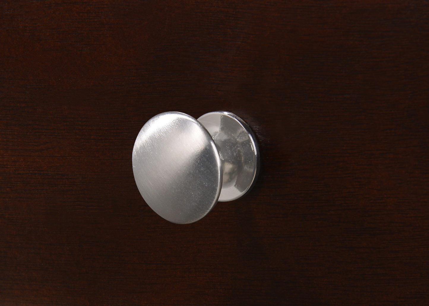 Brushed nickel cabinet knob on dark wood furniture