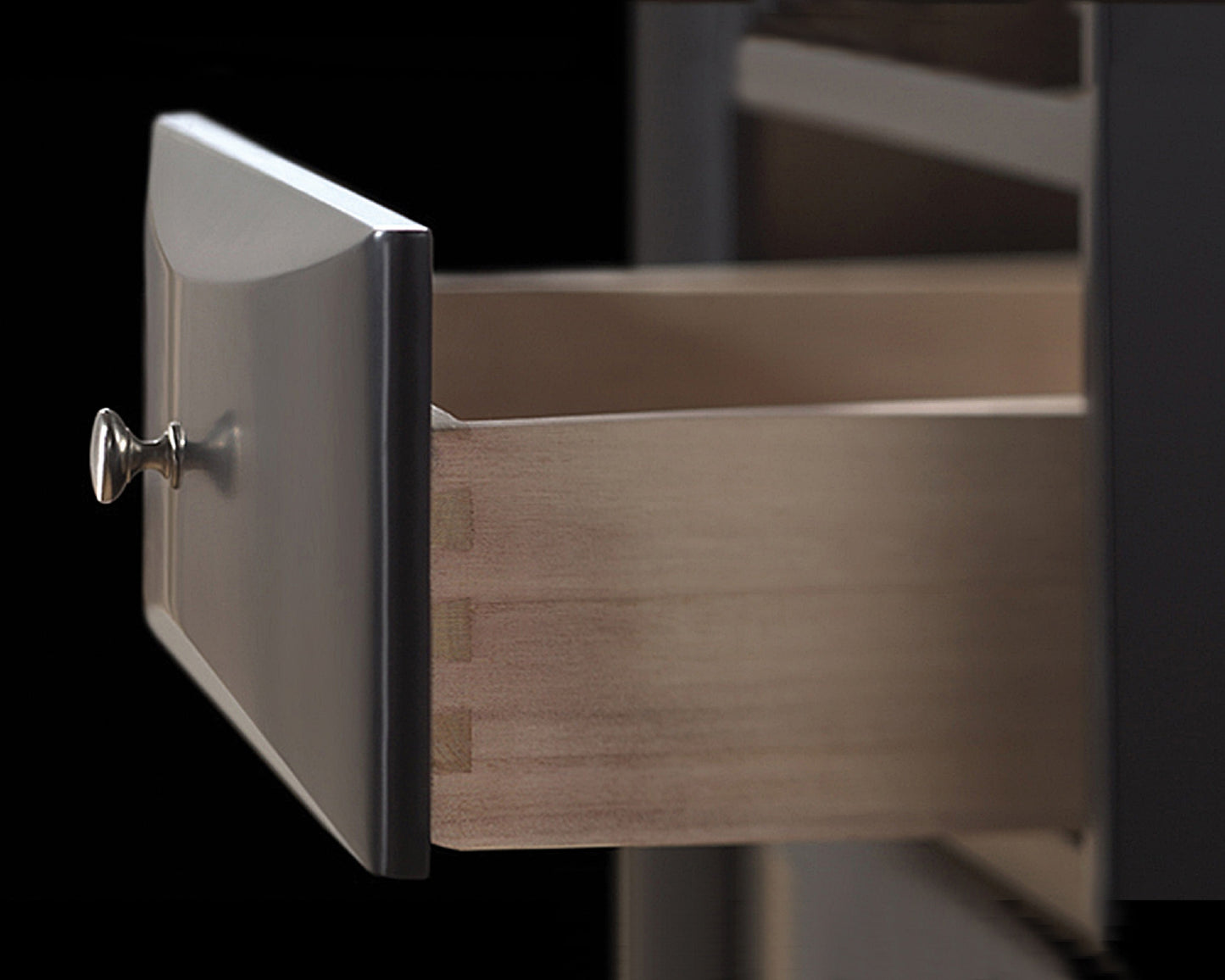 Dark wood dresser drawer with a brushed nickel knob showcasing dovetail joinery