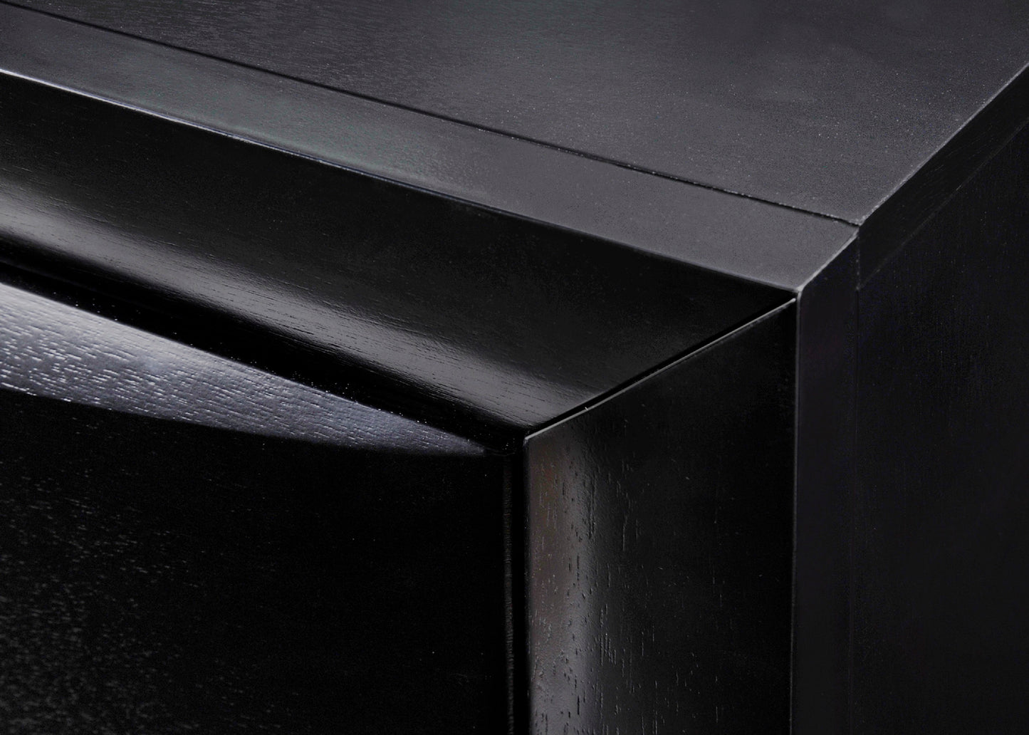Closeup of a glossy black wooden drawer with subtle wood grain texture