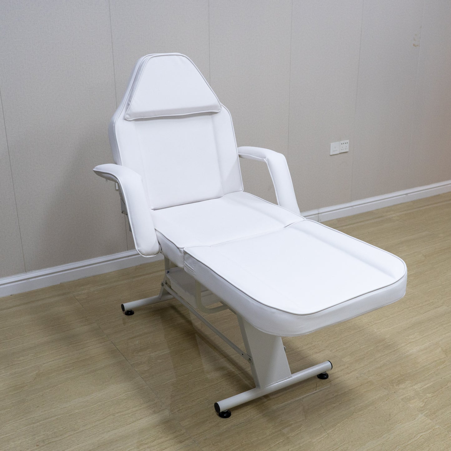 White adjustable massage bed with padded headrest and armrests for spa treatments
