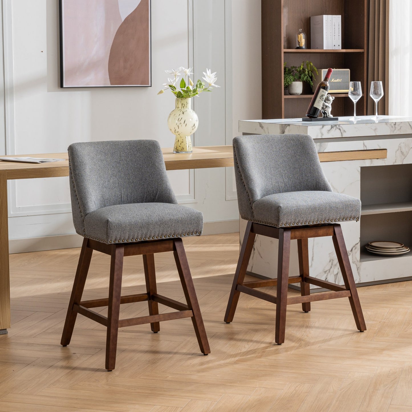 Two grey upholstered swivel bar stools with nailhead trim and dark wood legs