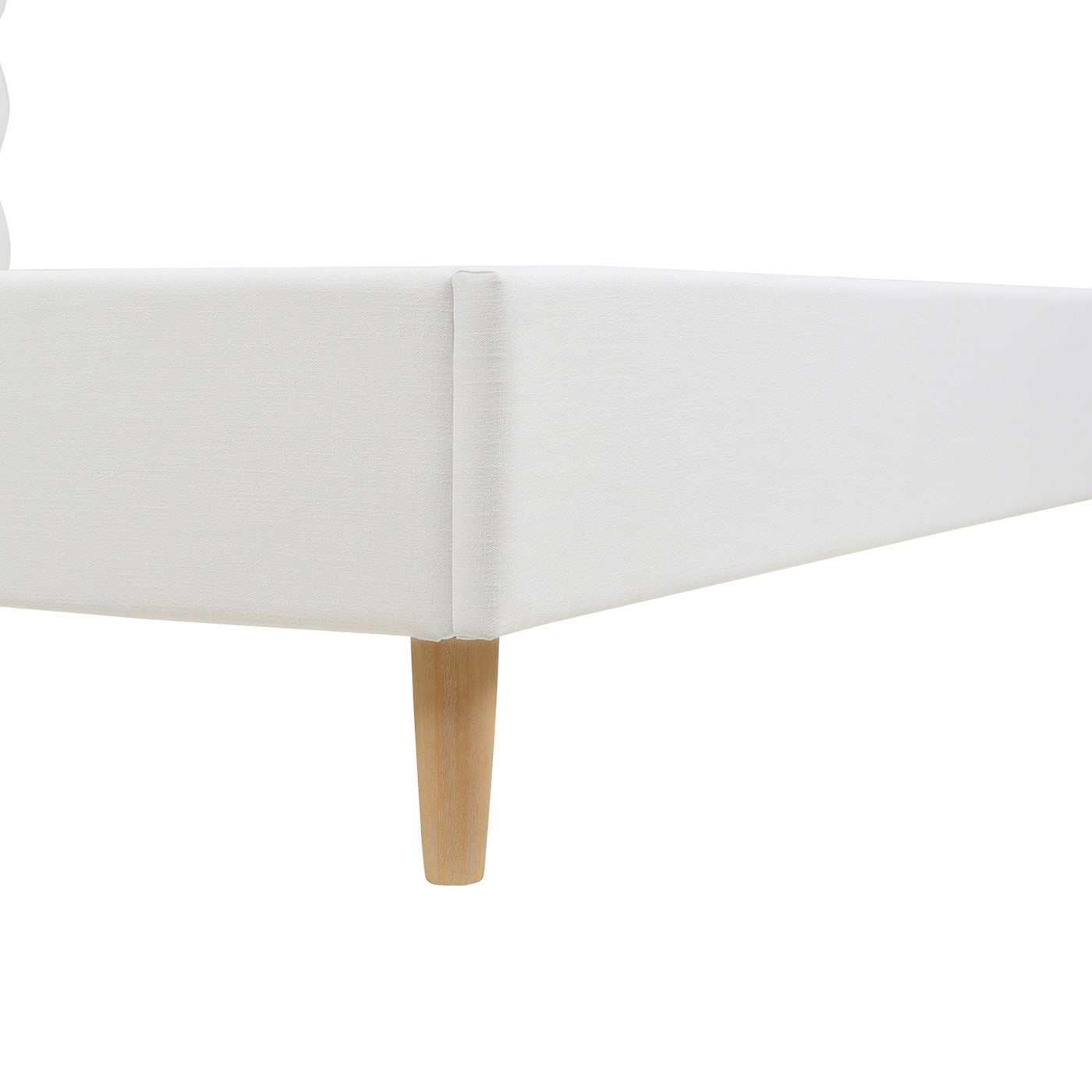 White fabric bed frame detail with tapered wooden legs