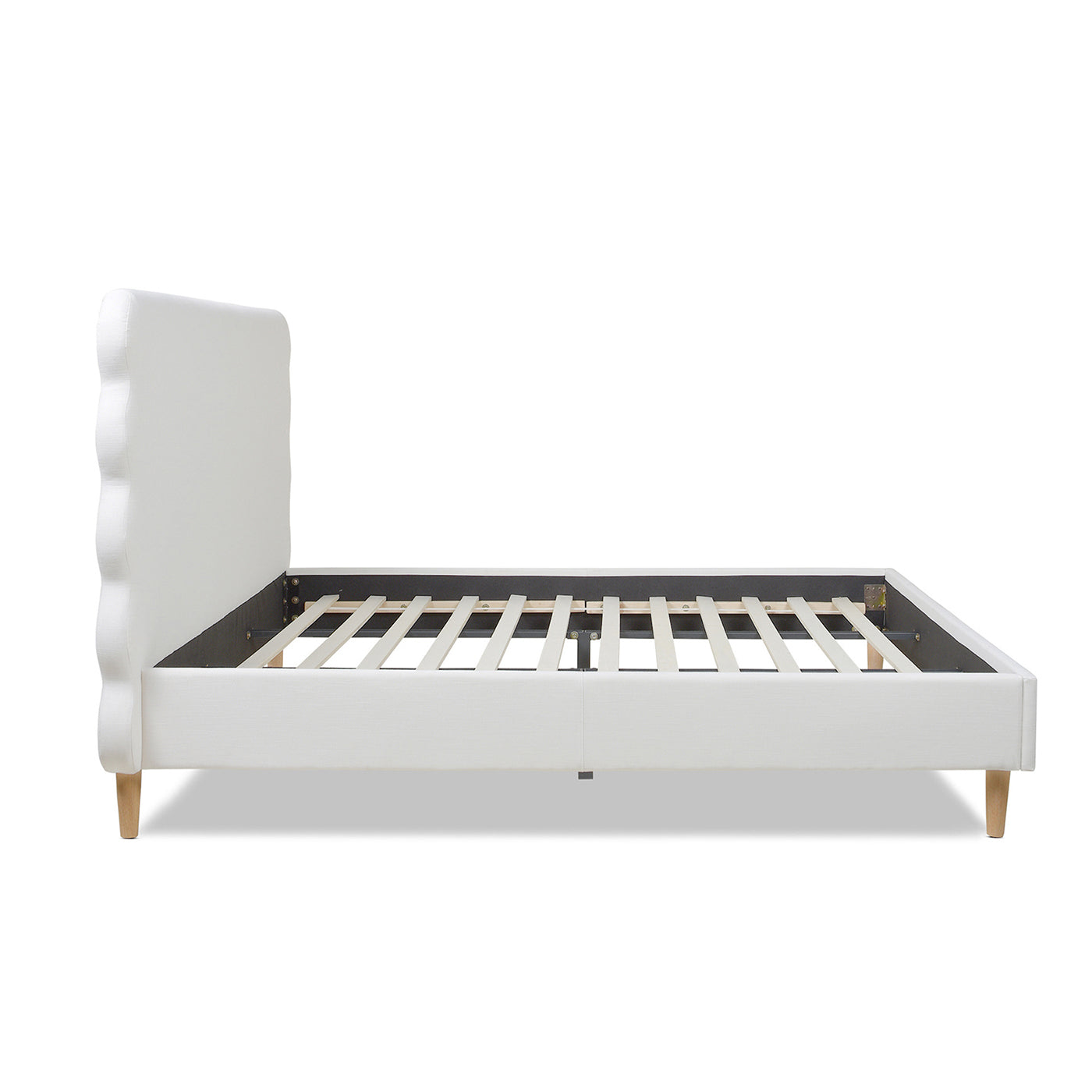 White upholstered platform bed frame with scalloped headboard and wooden legs