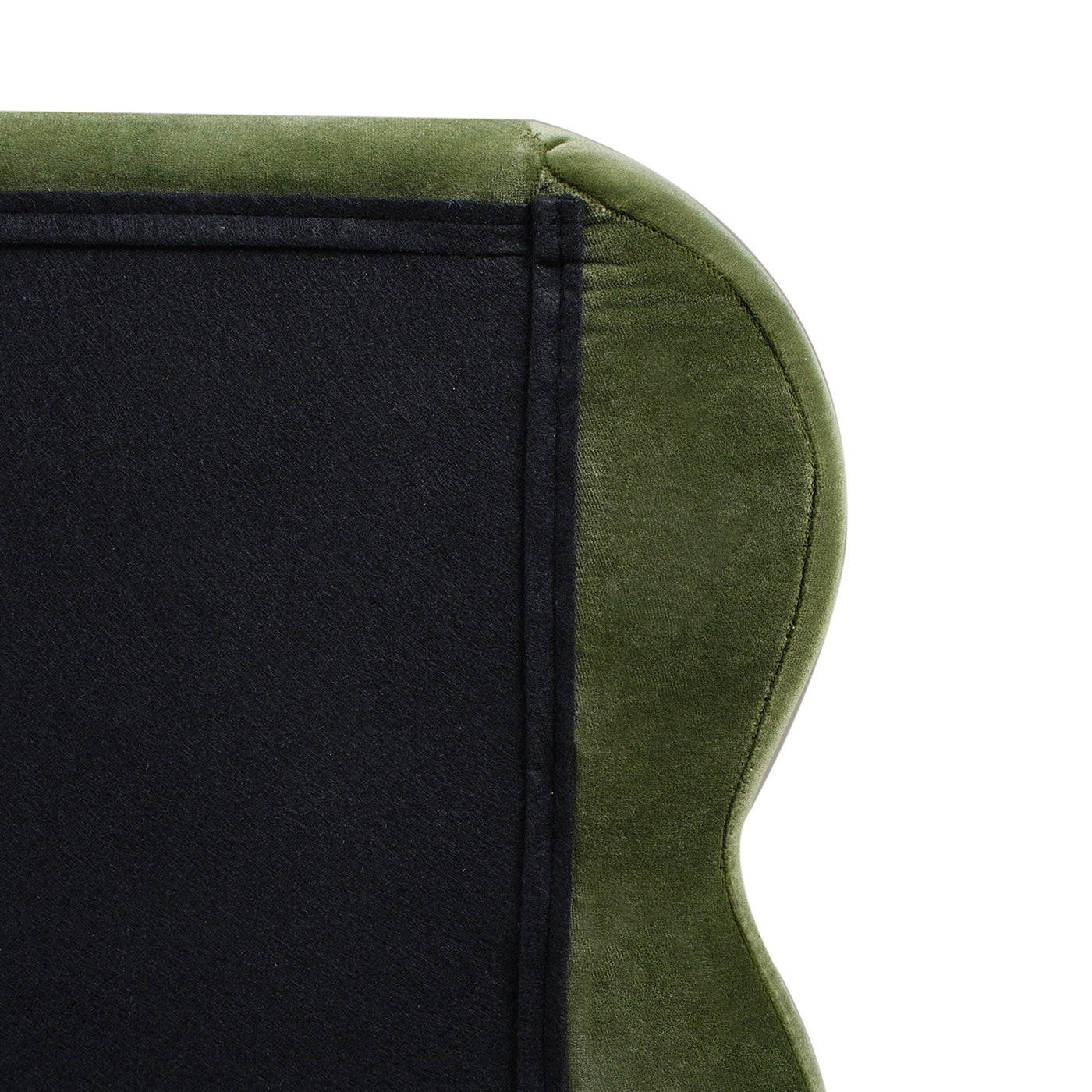 Closeup of plush green velvet upholstery detail on a chair back revealing black backing fabric