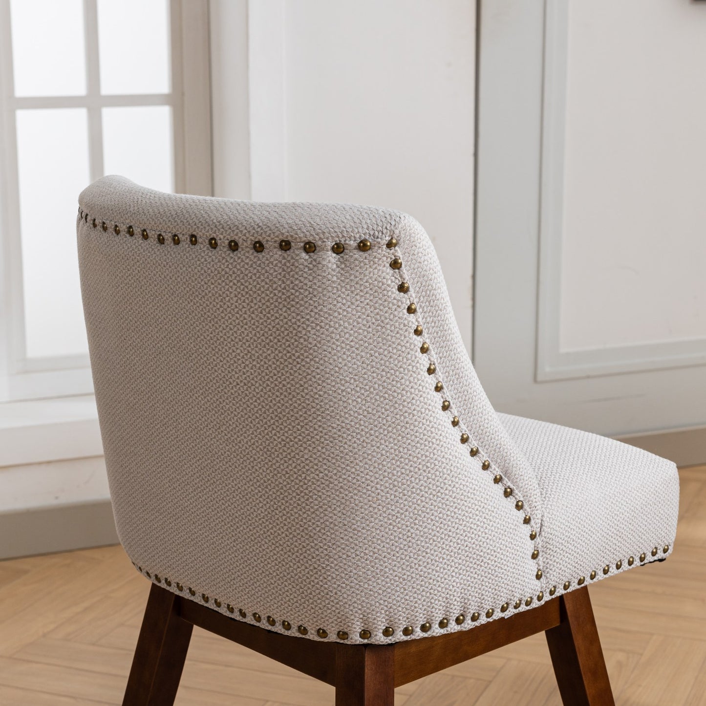 Light beige upholstered dining chair with brass nailhead trim detail