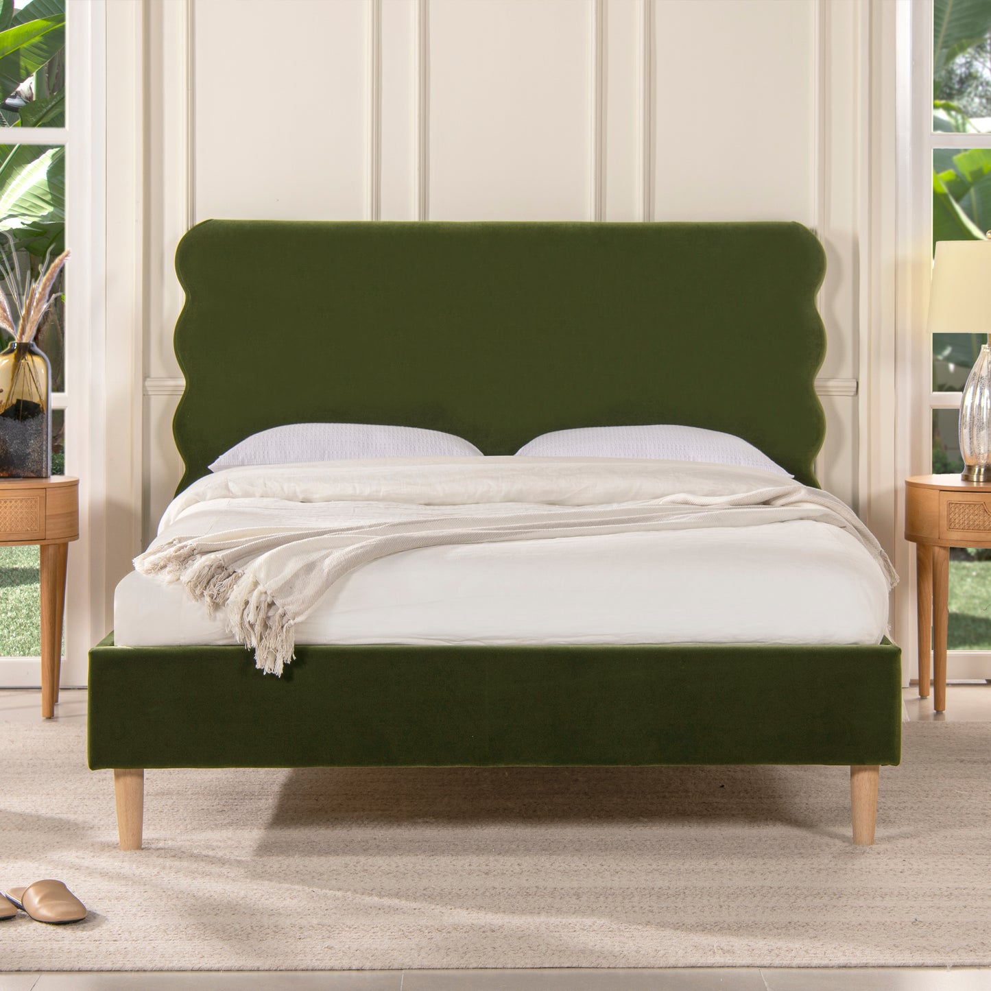 Emerald green velvet platform bed with scalloped headboard and wooden legs