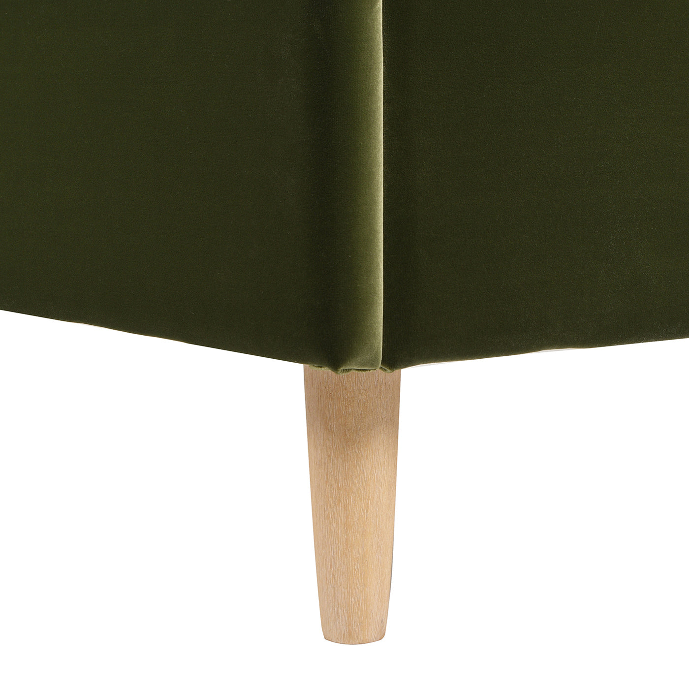 Deep green velvet sofa corner with tapered natural wood legs