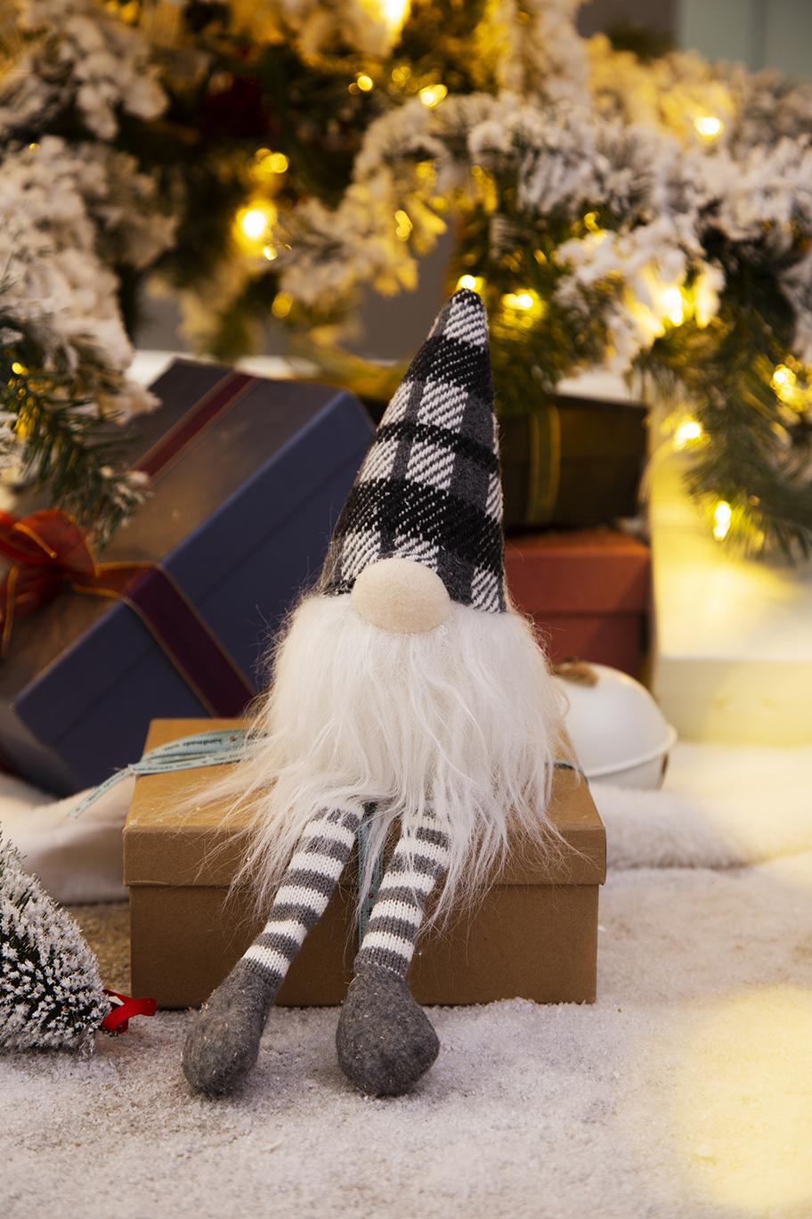 Plush gnome with white beard and checkered hat sits on a gift box festive decor