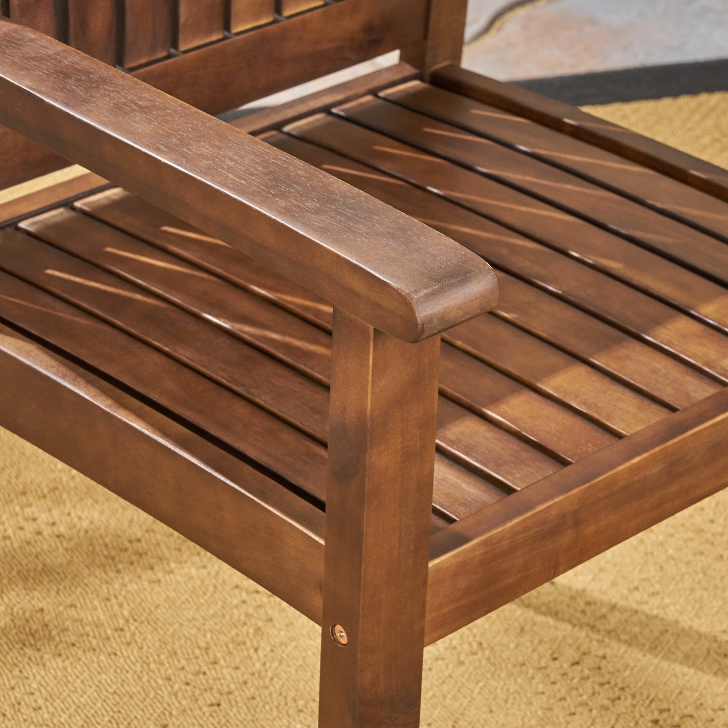 Closeup of a rich brown wooden Adirondack chair armrest showcasing its slatted design and outdoor patio setting