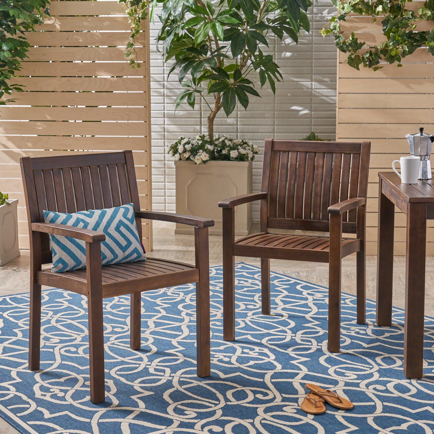 Two dark brown wooden dining chairs with blue patterned cushions on a blue and white rug