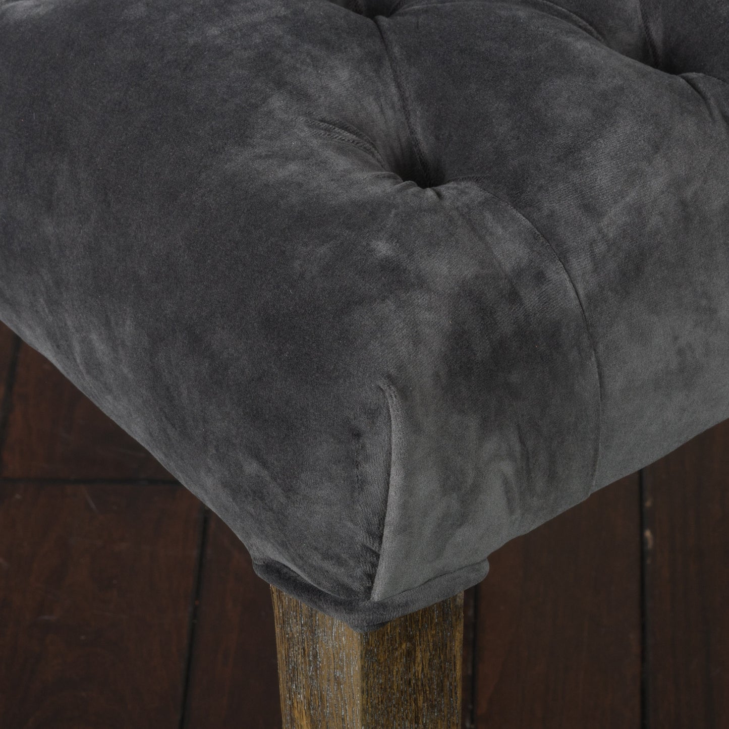 Dark gray velvet tufted ottoman with a distressed wood leg