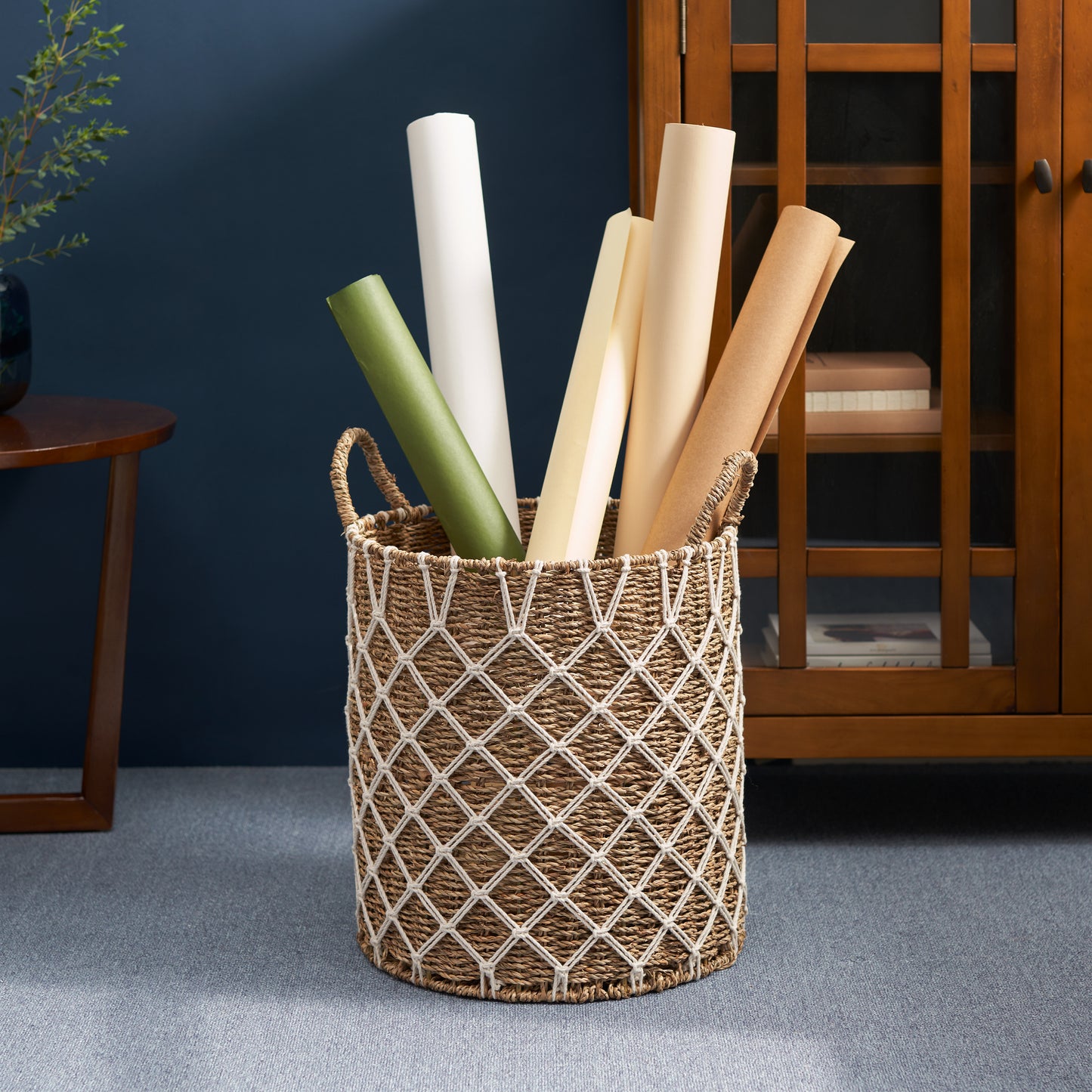 Woven seagrass storage basket with macrame detail holding rolled paper