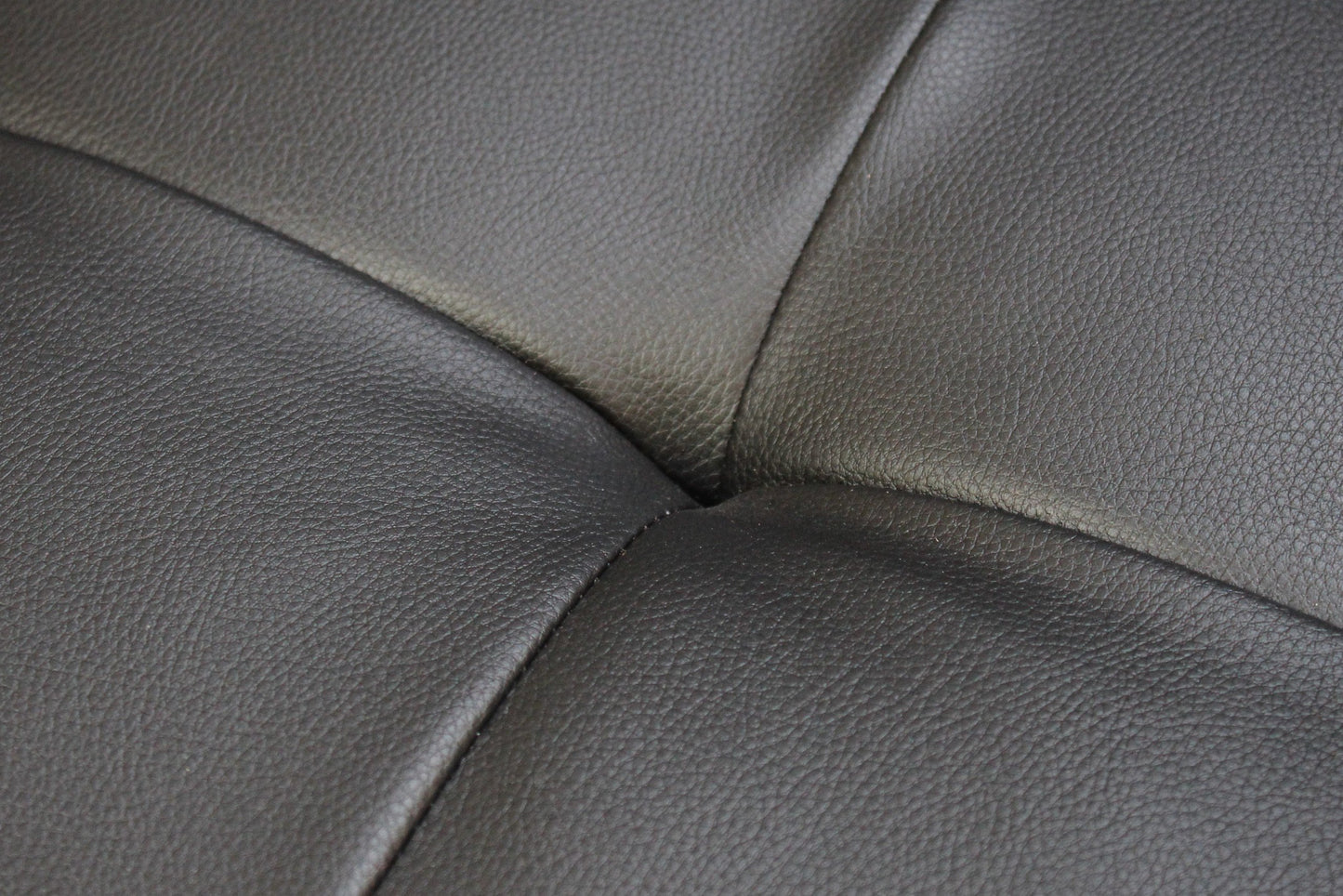 Closeup of dark grey textured leather sofa upholstery with visible stitching