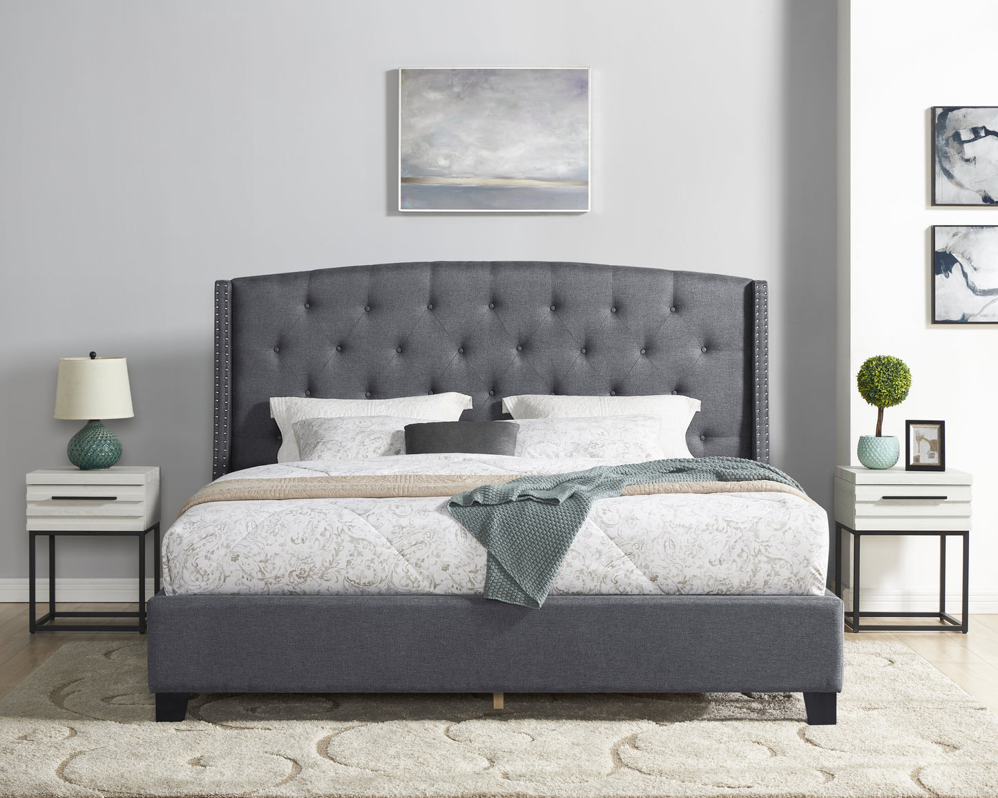 Dark grey fabric upholstered bed with tufted headboard and nailhead trim