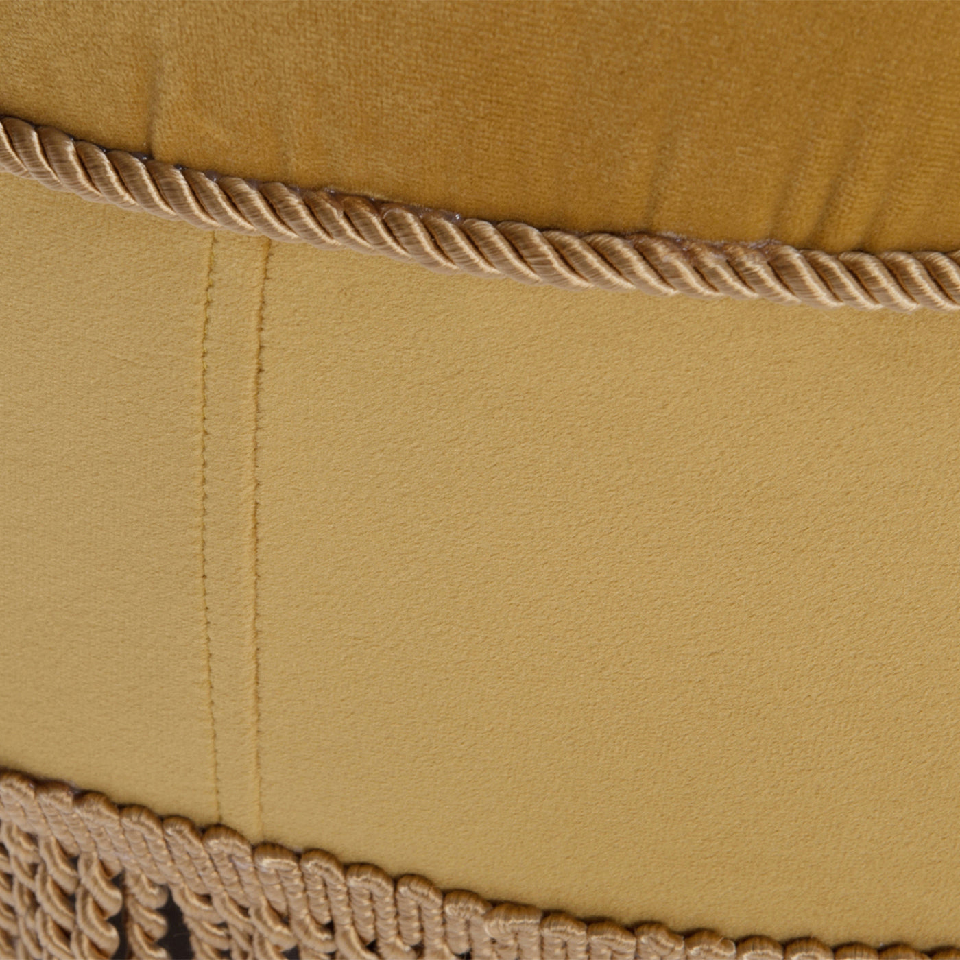 Closeup of textured mustard yellow velvet fabric with ornate gold rope trim