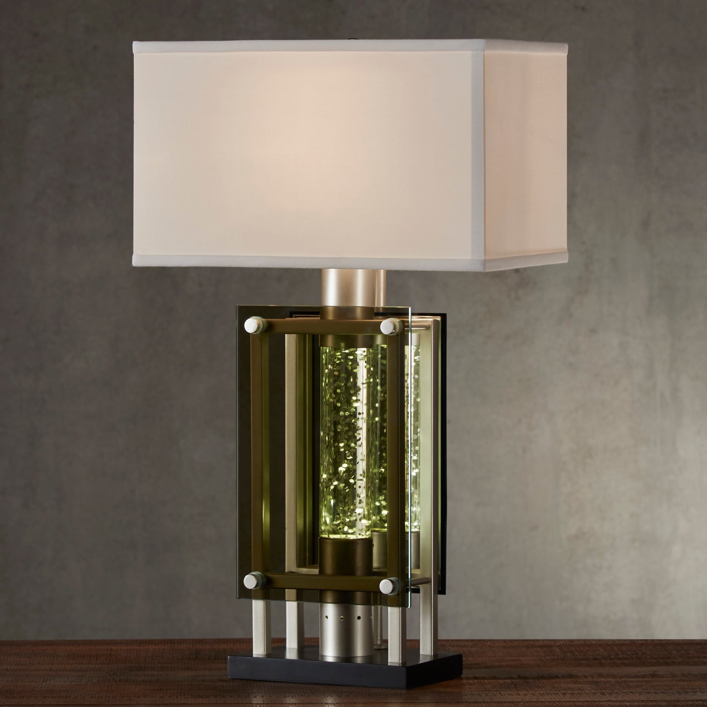 Modern desk lamp with a clear glass cylinder filled with shimmering golden accents