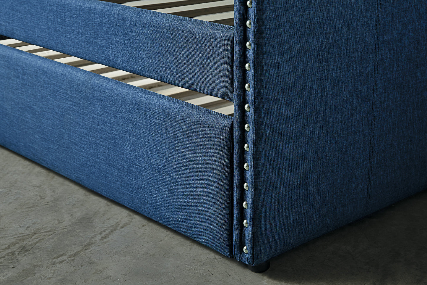 Closeup of a navy blue upholstered bed frame with silver nailhead trim detailing