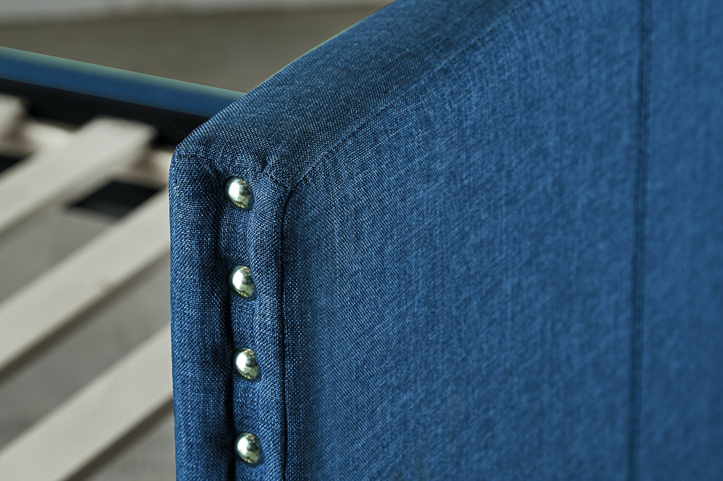 Closeup of a navy blue upholstered headboard with silver nailhead trim detail