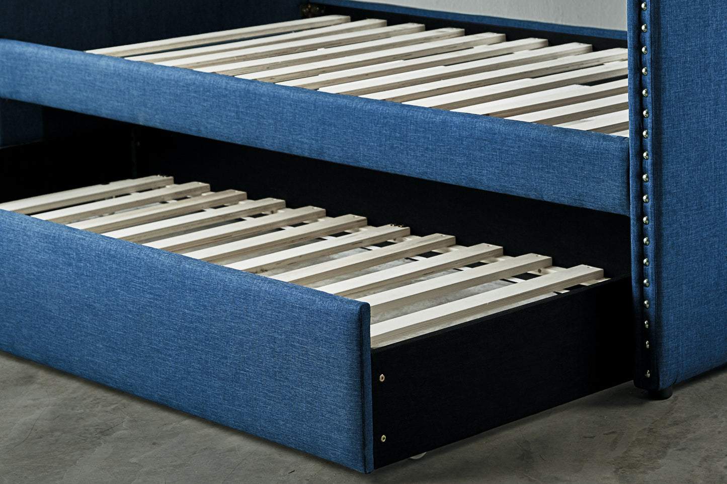 Navy blue upholstered bed frame with pullout trundle drawer and slatted base