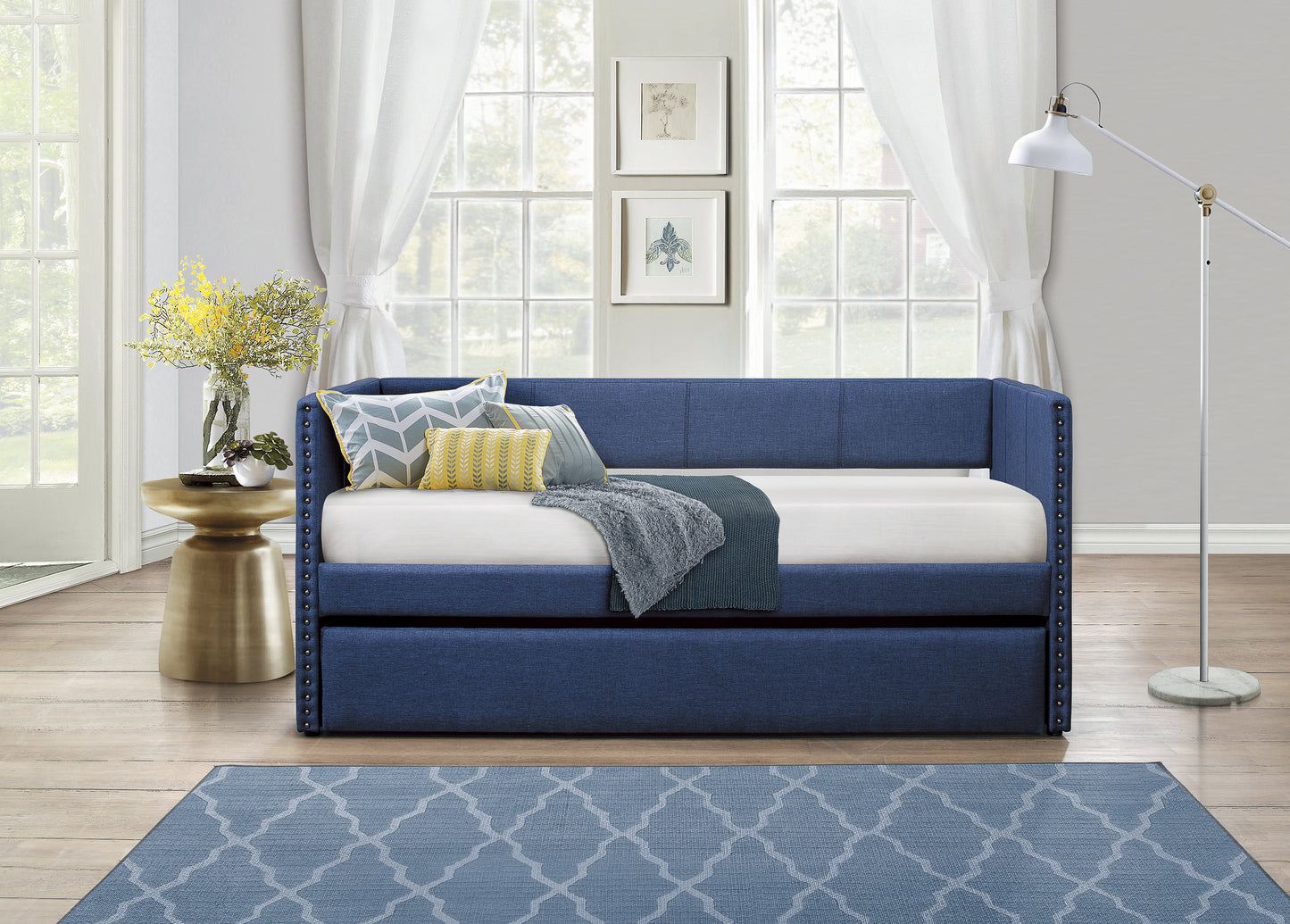 Tufted navy blue upholstered daybed with gold nailhead trim and decorative pillows