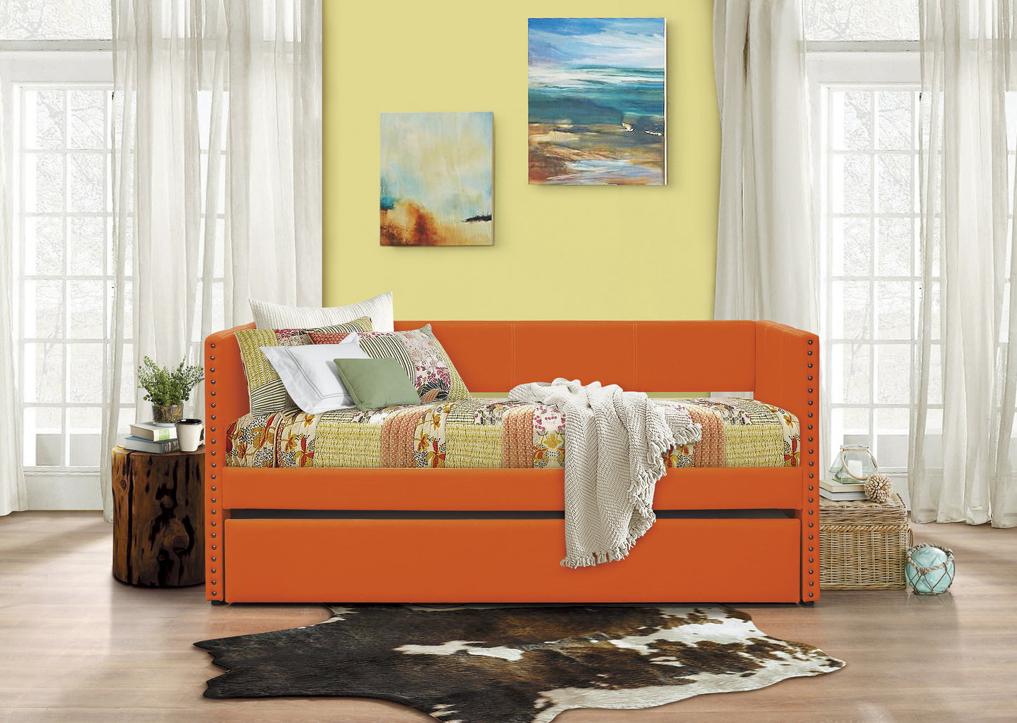 Orange tufted upholstered daybed with a patterned quilt and pillows