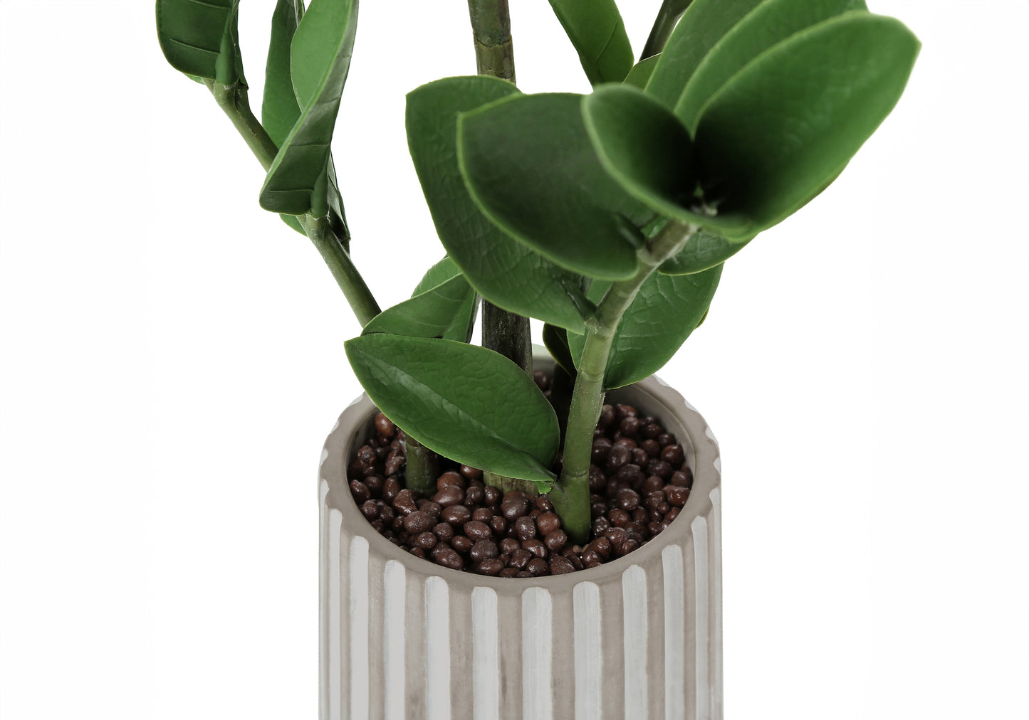 Closeup of a faux ZZ plant with glossy green leaves in a textured grey pot