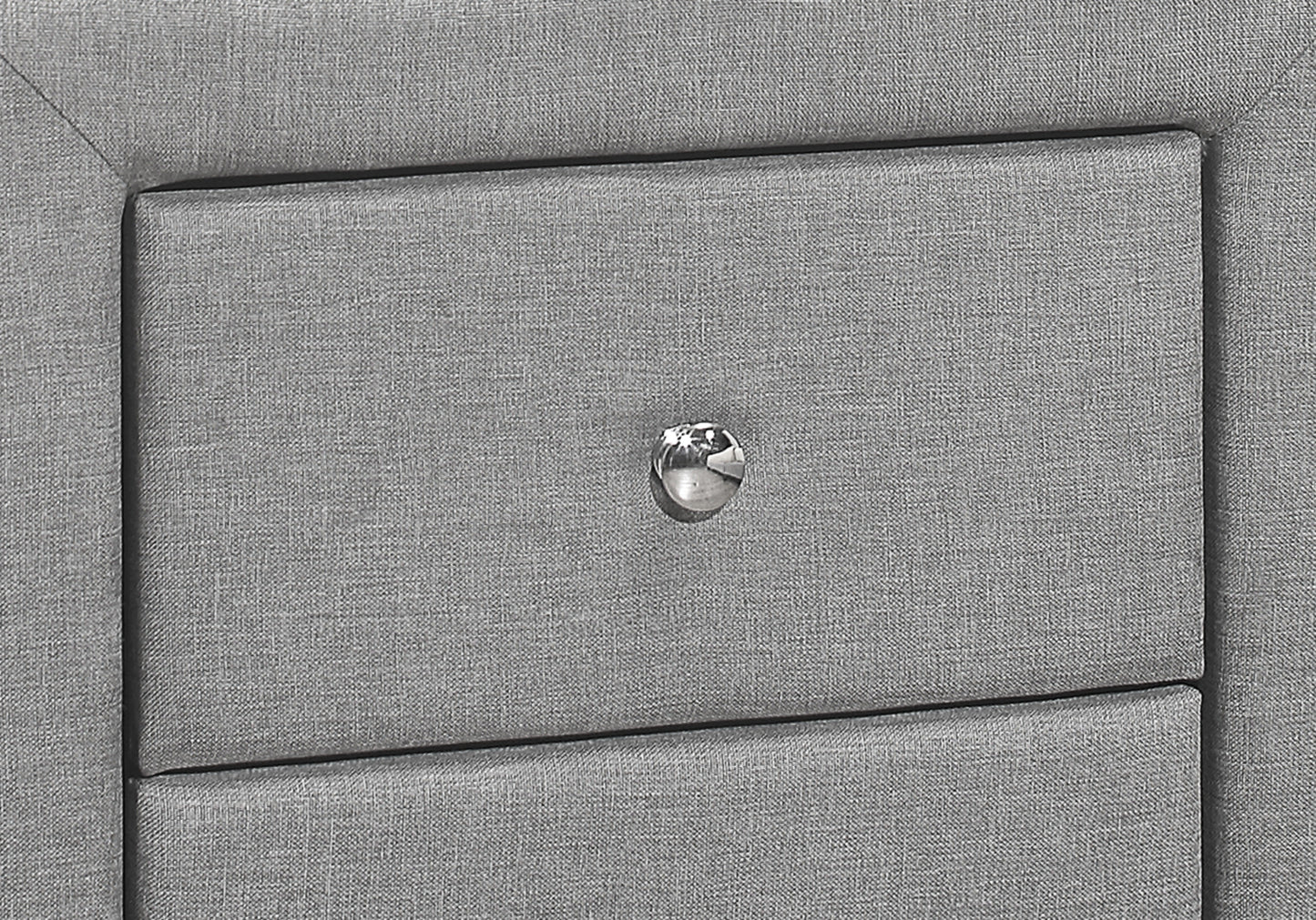 Closeup of a textured grey upholstered nightstand with a crystal knob