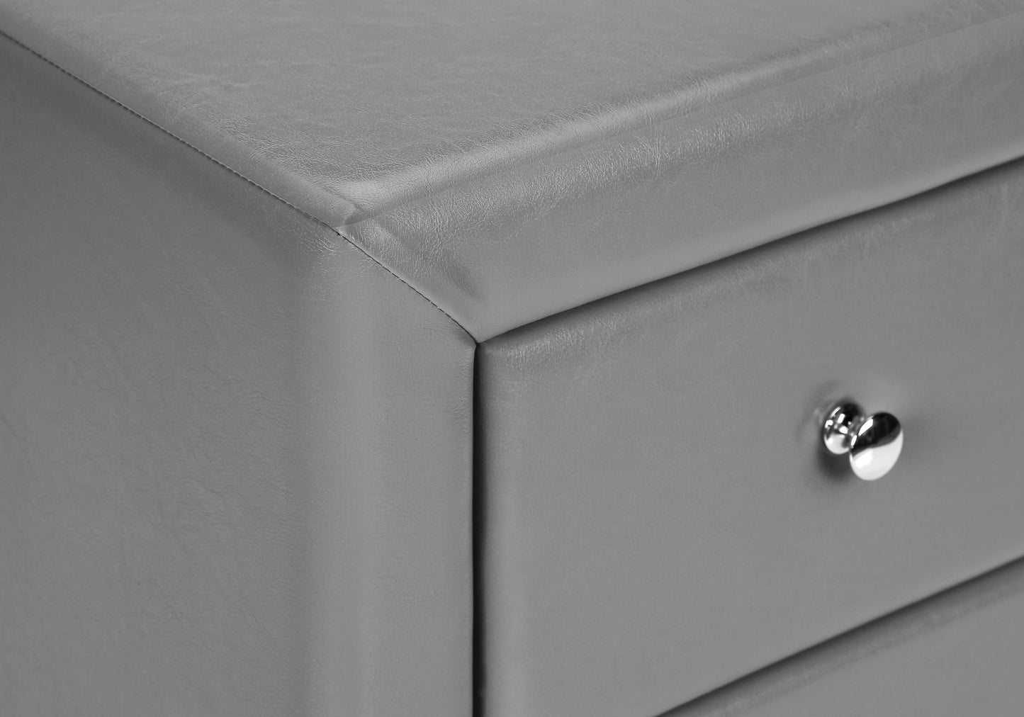Closeup of grey faux leather drawer with polished chrome knob