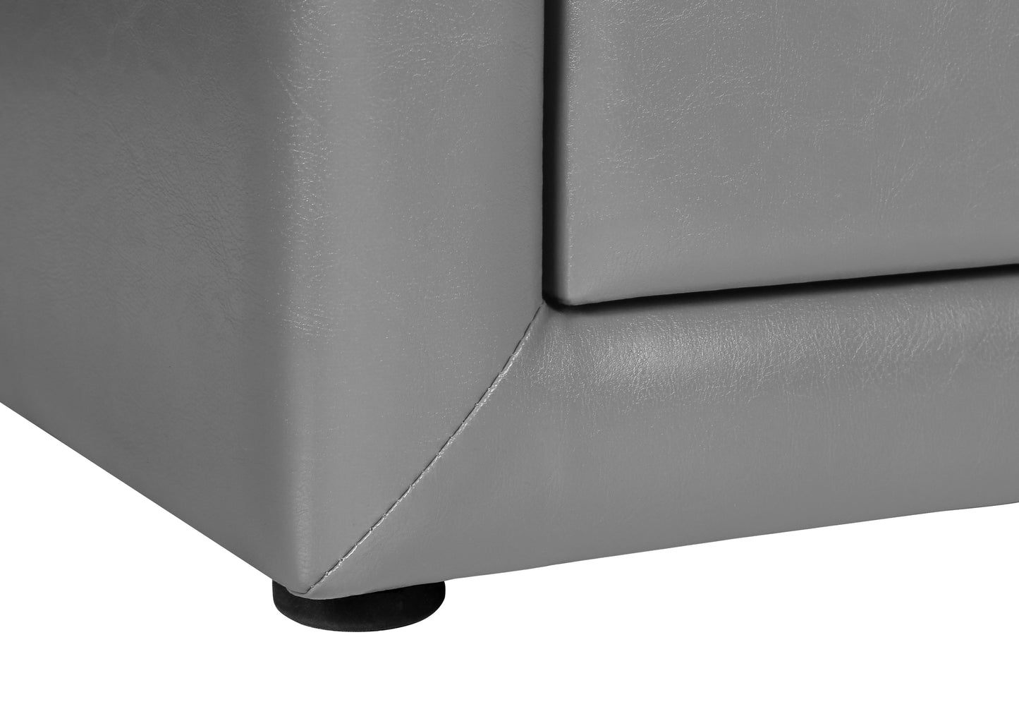Closeup of a grey faux leather couch corner with a visible black foot