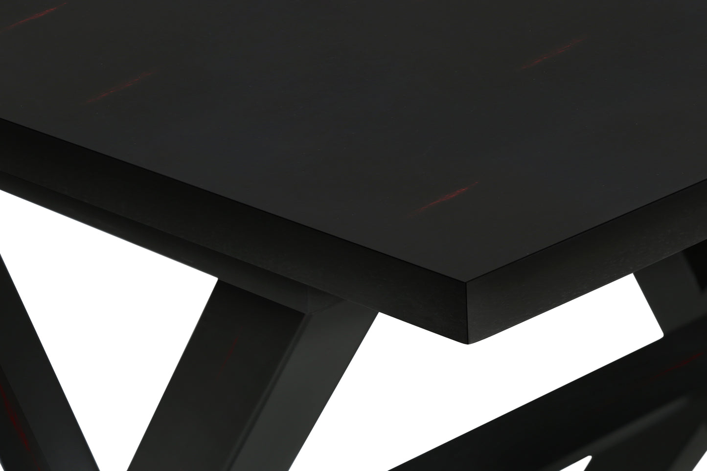Closeup of a black dining table with subtle red wood grain details on its surface