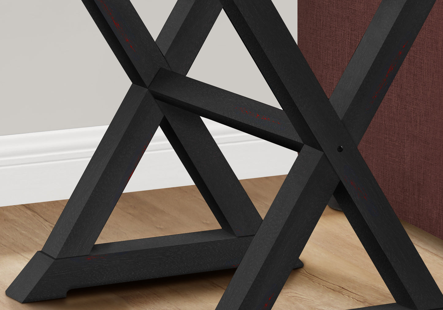 Black wooden trestle table base with subtle red accents featuring an Xframe design