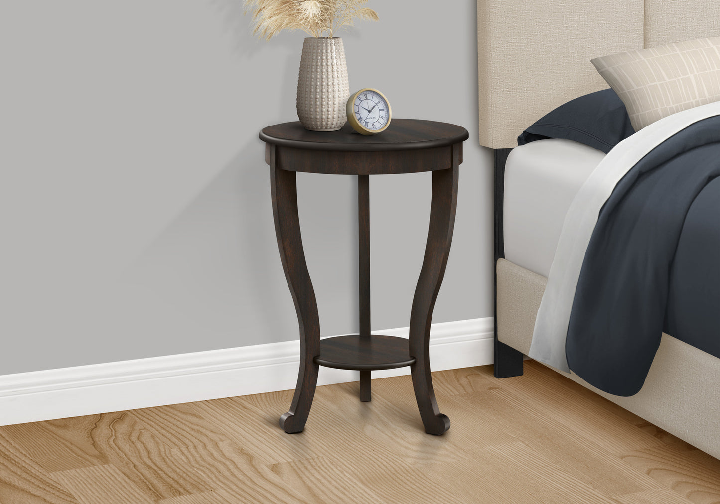 Dark wood round accent table with decorative vase and alarm clock
