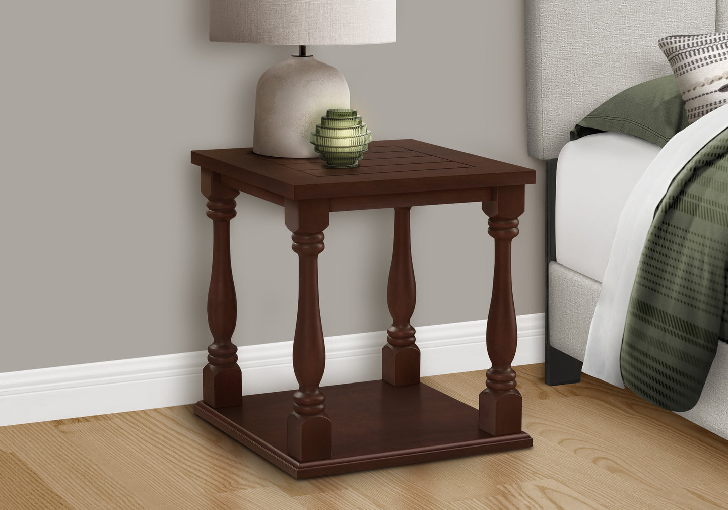Dark wood accent table with turned legs beside a bed