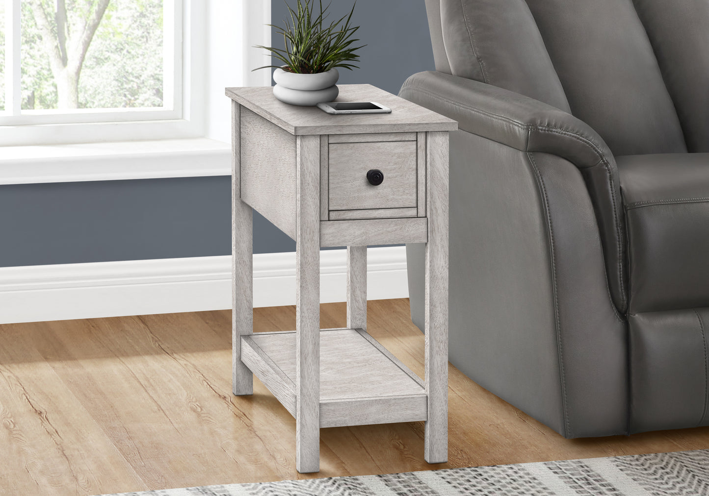 Light gray wood end table with one drawer and a lower shelf beside a recliner