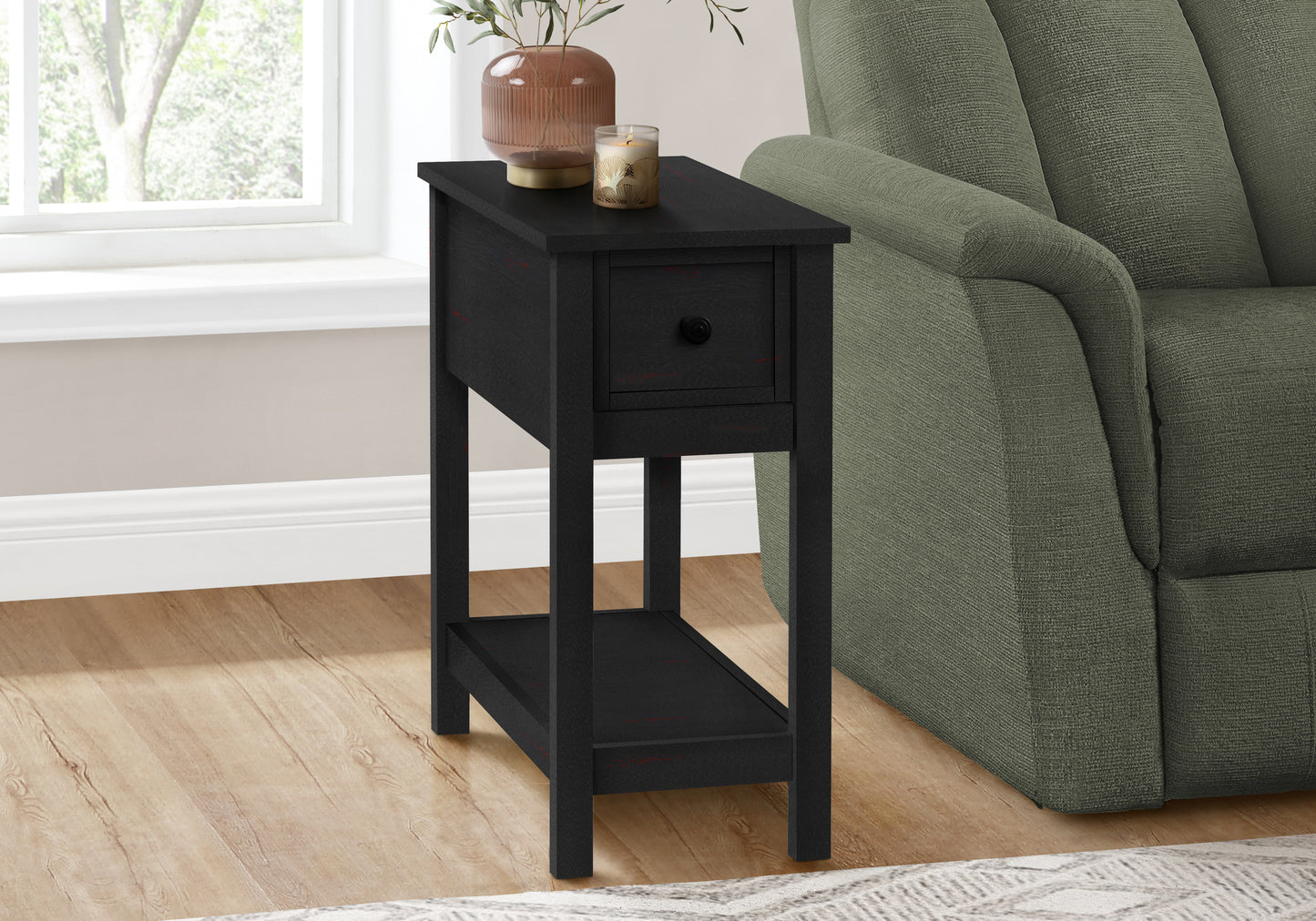Narrow black end table with one drawer and lower shelf beside sofa