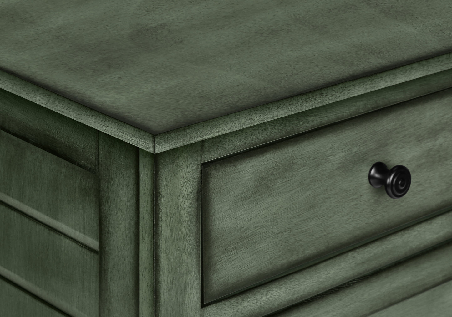 Closeup of weathered sage green wood nightstand drawer with black knob