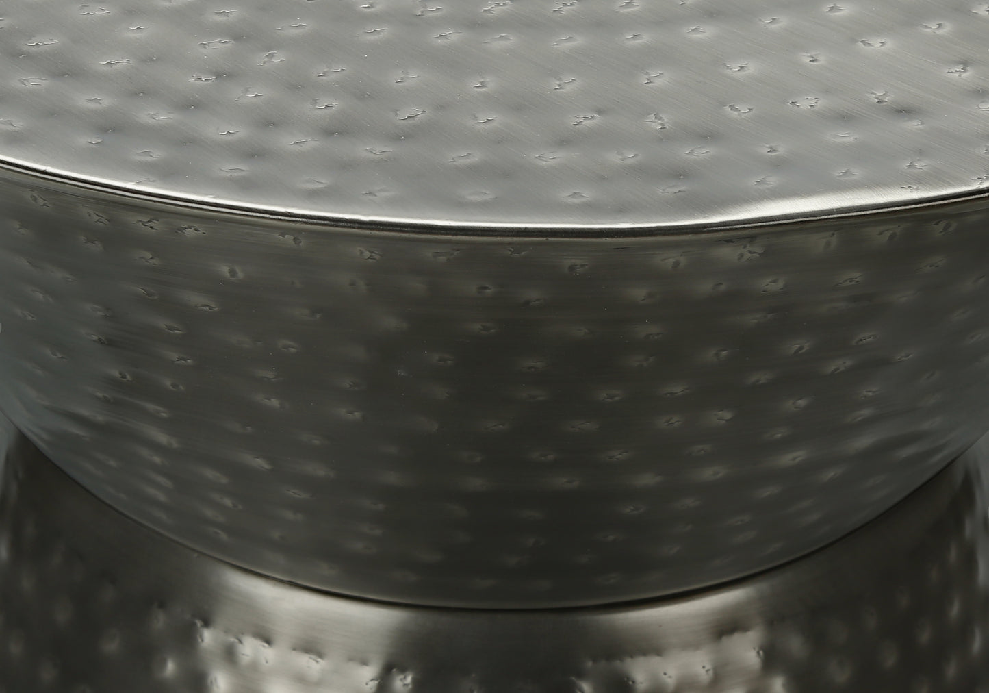 Closeup of a textured metallic accent table with a hammered finish and curved edges