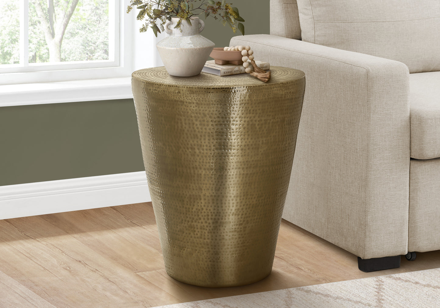 Hammered brass accent table with decorative vase and books